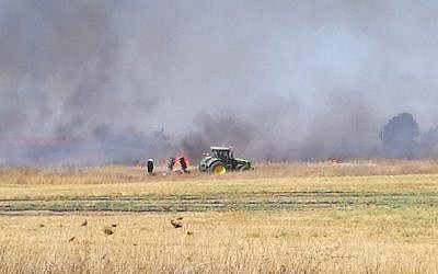 A farmer responds to a fire that broke out in his field outside Kibbutz Mefalsim in southern Israel, which was sparked by an incendiary kite from the Gaza Strip, on June 11, 2018. (Gali Kochba/Kibbutz Movement)