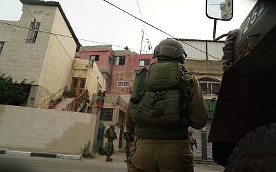 Israeli troops on June 6, 2018, arrest a Palestinian man suspected of killing an IDF soldier by dropping a stone slab on his head in the al-Am'ari refugee camp in Ramallah the month before. (Israel Defense Forces)