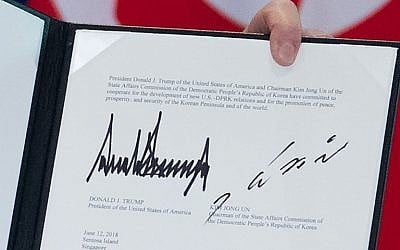 The signatures of US President Donald Trump (L) and North Korea's leader Kim Jong Un (R) are seen on a document held up by Trump following a signing ceremony during their historic US-North Korea summit, at the Capella Hotel on Sentosa island in Singapore, on June 12, 2018. ( AFP PHOTO / SAUL LOEB)