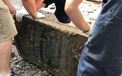 Volunteers rescue a Jewish headstone used to pave a street in the western Ukraine city Lviv, one of up to 100 headstones discovered during roadwork in the center of the city in June 2018. (Marla Raucher Osborn, Rohatyn Jewish Heritage/via JTA)