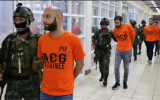 In this photo provided by the Philippine National Police, SAF (Special Action Force) members escort Israeli nationals following a raid at Clark Freeport Zone, Pampanga province, June 7, 2018, in Quezon city, northeast of Manila, Philippines. (Philippine National Police via AP)