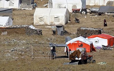 A picture taken on June 30, 2018, from the Golan Heights shows refugees building a new tent at a camp for displaced Syrians near the Syrian village of Burayqah in the southern province of Quneitra. (AFP/ JALAA MAREY)