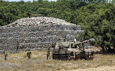 IDF soldiers walk past a bunker with a mobile artillery piece deployed near the border with Syria on the Israeli Golan Heights on July 1, 2018. (AFP Photo/Jalaa Marey)