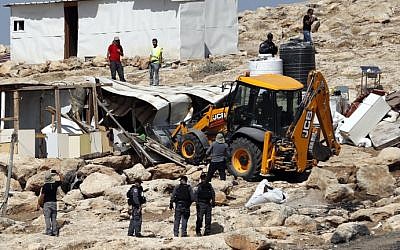 Israeli police secure a bulldozer demolishing structures at the Bedouin village of Abu Nuwar, east of Jerusalem in the West Bank on July 4, 2018. (AHMAD GHARABLI/AFP)