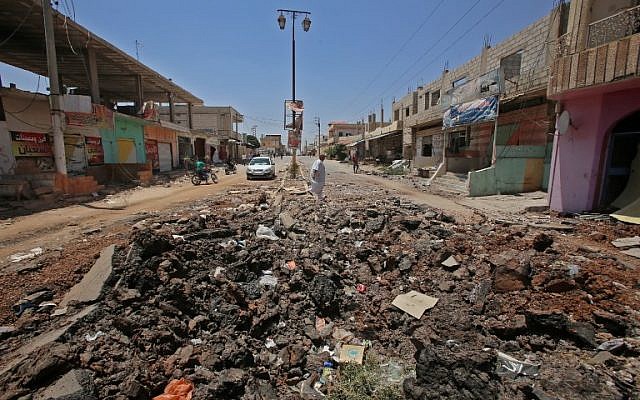A Syrian civilian walks past a shell hole after Syrian government forces recently recaptured the village of Ghariyah ash Sharqiyah from the rebels, in the province of Deraa, on July 4, 2018. (AFP/Youssef Karwashan) A Syrian civilian walks past a shell hole after Syrian government forces recently recaptured the village of Ghariyah ash Sharqiyah from the rebels, in the province of Deraa, on July 4, 2018. (AFP/Youssef Karwashan)