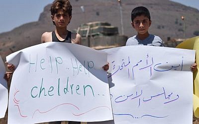 Displaced Syrian children hold signs during a protest in front of a UN base in the province of Quneitra, southwestern Syria, near the border with the Israeli Golan Heights, demanding the United Nations to help the stranded displaced in Syria-Israel and Syria-Jordan borders on July 4, 2018. (AFP PHOTO / Mohamad YUSUF)