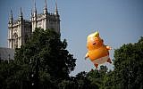 Pedestrians walk past as a giant balloon depicting US President Donald Trump as an orange baby floats next to the towers of Westminster Abbey during a demonstration against Trump's visit to the UK in Parliament Square in London on July 13, 2018. (AFP PHOTO / Tolga AKMEN)