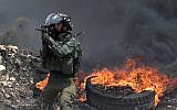An Israeli soldier fires a rubber bullet towards Palestinian protesters during clashes  near Nablus, in the West Bank on July 13, 2018. ( AFP PHOTO / JAAFAR ASHTIYEH)