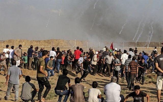 Illustrative. Tear gas canisters fired by Israeli forces land amid Palestinians during clashes along the border with Israel east of Gaza City on July 13, 2018. (AFP Photo/Mahmud Hams) Illustrative. Tear gas canisters fired by Israeli forces land amid Palestinians during clashes along the border with Israel east of Gaza City on July 13, 2018. (AFP Photo/Mahmud Hams)
