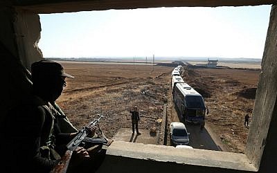A member of Hayat Tahrir al-Sham group, led by Syria's former Al-Qaeda affiliate, watches as a convoy of buses gets ready to enter the towns of Fuaa and Kefraya to evacuate their residents on July 18, 2018. (AFP PHOTO / OMAR HAJ KADOUR)