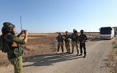 Members of Hayat Tahrir al-Sham group, led by Syria's former Al-Qaeda affiliate, have their picture taken in front of a convoy of buses getting ready to enter the towns of Fuaa and Kefraya, in Syria, to evacuate their residents on July 18, 2018. (AFP Photo/Omar Haj Kadour)