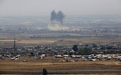 A picture taken from the Israeli Golan Heights shows smoke rising above buildings during unidentified air strikes across the border fence opposite a camp for displaced Syrians near the village of al-Rafeed in the southern Syrian province of Daraa, July 18, 2018. (JALAA MAREY/AFP)