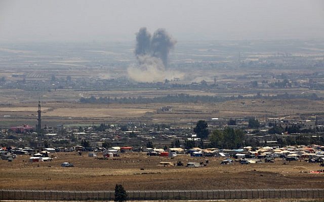 A picture taken from the Israeli Golan Heights shows smoke rising above buildings during unidentified air strikes across the border fence opposite a camp for displaced Syrians near the village of al-Rafeed in the southern Syrian province of Daraa, July 18, 2018. (JALAA MAREY/AFP) A picture taken from the Israeli Golan Heights shows smoke rising above buildings during unidentified air strikes across the border fence opposite a camp for displaced Syrians near the village of al-Rafeed in the southern Syrian province of Daraa, July 18, 2018. (JALAA MAREY/AFP)