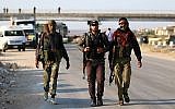 Syrian rebel fighters from the Quneitra province walk with their rifles as they wait at the Morek crossing point to be transfered in the provinces of Idlib and Aleppo on July 21, 2018. (AFP Photo/Aaref Watad)