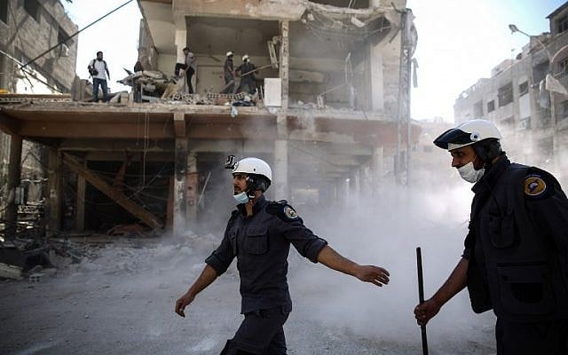 In this photo taken on October 5, 2016, Syrian civil defense volunteers, known as the White Helmets, work around destroyed buildings following reported airstrikes on the rebel-held town of Douma, on the eastern outskirts of the capital Damascus. (AFP PHOTO / Sameer Al-Doumy)