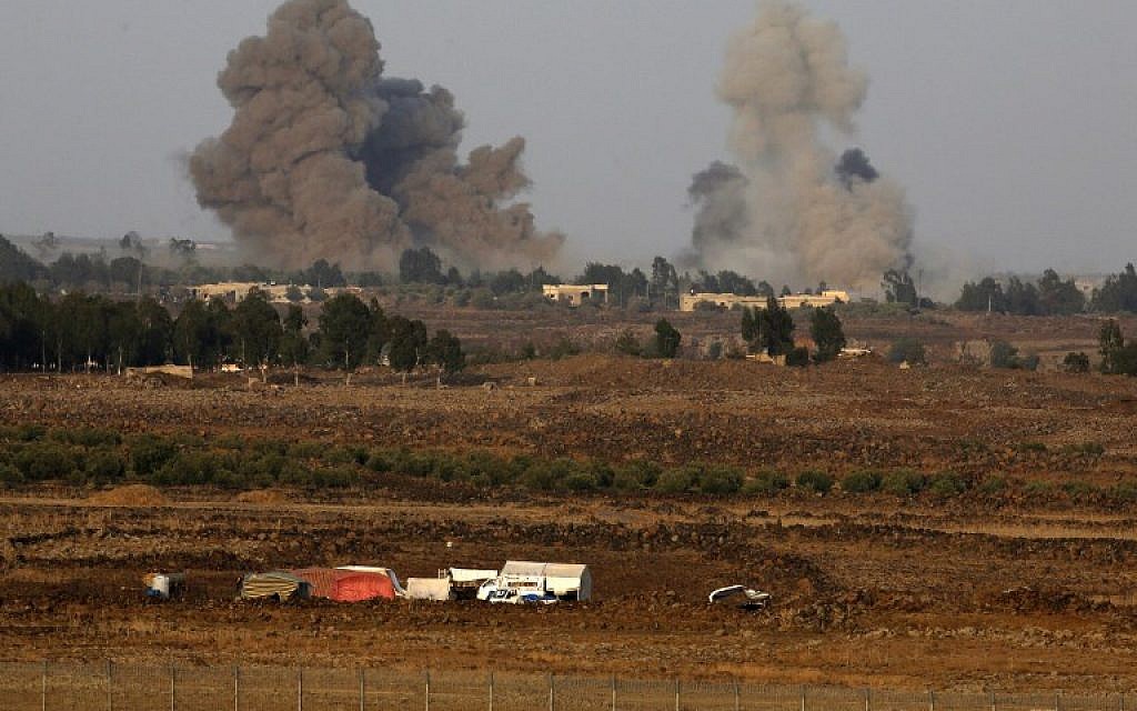 A picture taken on July 24, 2018 from the Tal Saki hill in the Golan Heights shows smoke rising above buildings across the border in Syria during air strikes backing a Syrian-government-led offensive in the southwestern province of Daraa. (AFP/ JALAA MAREY)