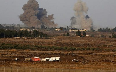 A picture taken on July 24, 2018 from the Tal Saki hill in the Golan Heights shows smoke rising above buildings across the border in Syria during air strikes backing a Syrian-government-led offensive in the southwestern province of Daraa. (AFP/ JALAA MAREY)