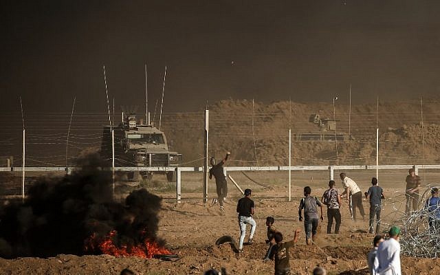 Illustrative: Palestinians throw stones towards Israeli soldiers during a demonstration along the border between Israel and the Gaza Strip, east of Gaza City on July 27, 2018. (AFP Photo/Mahmud Hams) Illustrative: Palestinians throw stones towards Israeli soldiers during a demonstration along the border between Israel and the Gaza Strip, east of Gaza City on July 27, 2018. (AFP Photo/Mahmud Hams)