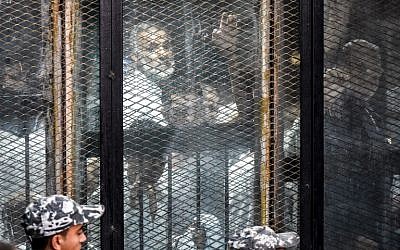 Essam el-Erian (R), one of the highest-ranking leaders of Egypt's banned Muslim Brotherhood, is seen alongside other members of the group inside a glass dock during their trial in the capital Cairo on July 28, 2018. (AFP Photo/Khaled Desouki)