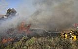Illustrative: Firefighters extinguish a blaze near the southern city of Sderot caused by an incendiary balloon launched from the Gaza Strip on July 31, 2018. (AFP Photo/Menahem Kahana)