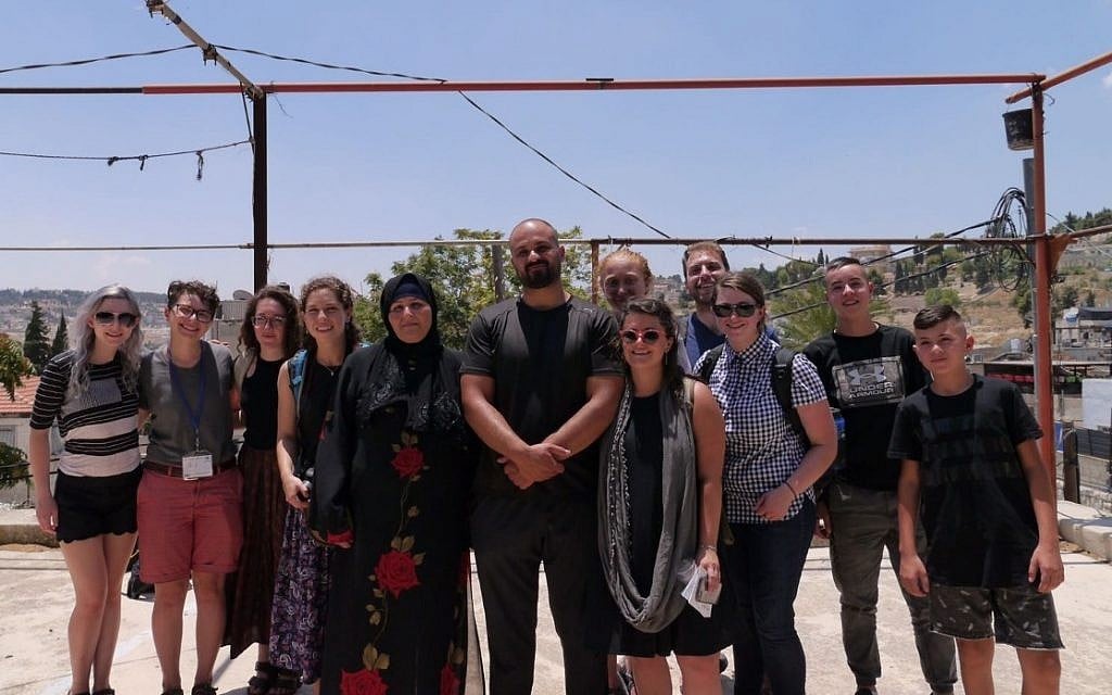 Left-wing activists who staged a walkout from their Birthright trip pose for a photo with members of the Sumarin family, who are facing eviction from their home in East Jerusalem on July 15, 2018. (Courtesy) Left-wing activists who staged a walkout from their Birthright trip pose for a photo with members of the Sumarin family, who are facing eviction from their home in East Jerusalem on July 15, 2018. (Courtesy)