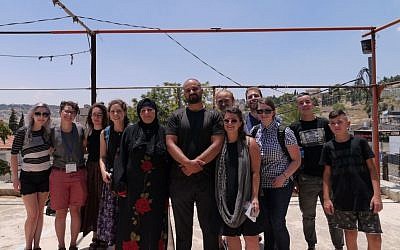 Left-wing activists who staged a walkout from their Birthright trip pose for a photo with members of the Sumarin family, who are facing eviction from their home in East Jerusalem on July 15, 2018. (Courtesy)