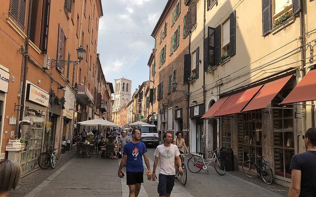 Via Mazzini, one of the cmain streets in the Ferrara, Italy, city center that used to be part of the Ghetto. The bell tower of the cathedral can be seen in the background, and the synagogue building under renovation is behind the truck. (Rossella Tercatin/ Times of Israel)