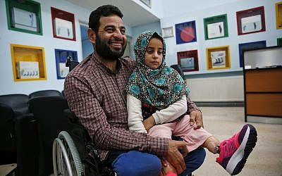 In this Thursday, July 5, 2018 photo, Syrian refugee Maya Meri, 8, sits on her father Mohammed's lap after being fitted with prosthetic legs at a rehabilitation clinic in Istanbul. (AP Photo/Lefteris Pitarakis)