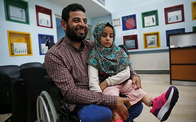 In this Thursday, July 5, 2018 photo, Syrian refugee Maya Meri, 8, sits on her father Mohammed's lap after being fitted with prosthetic legs at a rehabilitation clinic in Istanbul. (AP Photo/Lefteris Pitarakis) In this Thursday, July 5, 2018 photo, Syrian refugee Maya Meri, 8, sits on her father Mohammed's lap after being fitted with prosthetic legs at a rehabilitation clinic in Istanbul. (AP Photo/Lefteris Pitarakis)