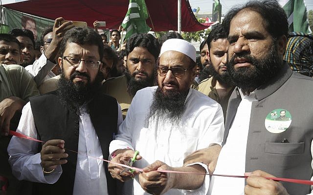 In this Sunday, July 8, 2018 photo, Hafiz Saeed, center, head of the Pakistani religious group Jamaat-ud-Dawa inaugurates an election office of the newly formed political party Allah-o-Akbar Tehreek, in Lahore, Pakistan (AP Photo/K.M. Chaudary)