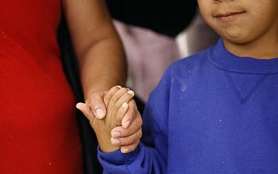 In this June 22, 2018, file photo, a mother, left, and son, from Guatemala, hold hands during a news conference following their reunion in Linthicum, Maryland, after being reunited following their separation at the US border. (AP Photo/Patrick Semansky, File)