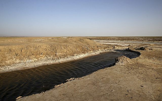 This Tuesday, July 10, 2018 photo shows one of the last puddles of salty water remaining in the Gavkhouni wetlands, which was once a swamp fed by the Zayandeh Roud river, and is now surrounded by desiccated salt-laced fields, outside the town of Varzaneh and its suburbs, home to 30,000 people some 550 kilometers (340 miles) south of the capital Tehran, Iran. (AP Photo/Vahid Salemi)