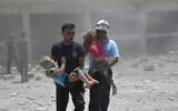 Civil defense workers known as the White Helmets carry children after airstrikes hit a school housing a number of displaced people, in the western part of the southern Daraa province of Syria, on June 14, 2017. (Syrian Civil Defense White Helmets via AP)