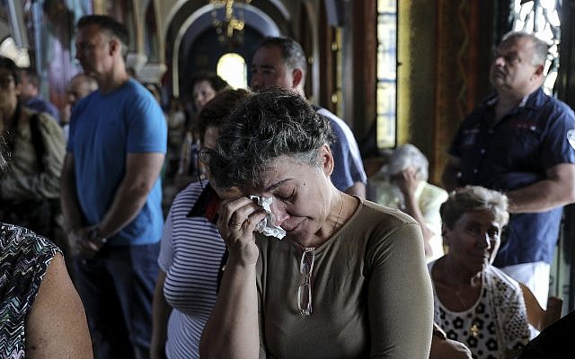 Greek Orthodox faithful attend a memorial service for the victims of a forest fire, inside a church at Mati village, east of Athens, July 29, 2018. (AP Photo/Yorgos Karahalis) Greek Orthodox faithful attend a memorial service for the victims of a forest fire, inside a church at Mati village, east of Athens, July 29, 2018. (AP Photo/Yorgos Karahalis)