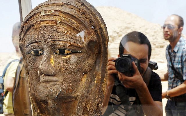 A photographer films a gilded silver mummy mask found on the face of the mummy of the second priest of Mut, as it is displayed during a press conference in front of the step pyramid of Saqqara, in Giza, Saturday, July 14, 2018. (AP/Amr Nabil)