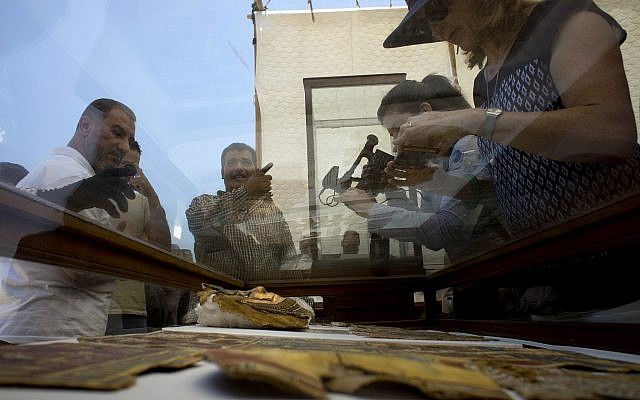 Reporters film recently discovered gilded mummy mask found in a disturbed context of the hall way of a burial chamber dating back some 2,500 years at an ancient necropolis near Egypt's famed pyramids in Saqqara, Giza, Saturday, July 14, 2018. (AP/Amr Nabil)