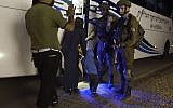 This image made from video released by the Israeli Defense Forces on Sunday, July 22, 2018 shows a member of the White Helmets waving to Israeli soldiers as he and his family board a bus to Jordan. (Israeli Defense Forces via AP)