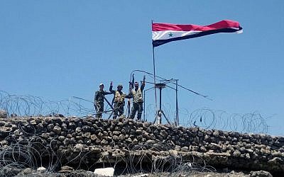 In this Tuesday, July 17, 2018, photo, released by the Syrian official news agency SANA, Syrian troops flash the victory sign next to the Syrian flag in Tell al-Haara, the highest hill in the southwestern Daraa province, Syria. (SANA via AP)