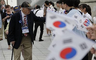 U.S. veteran of the Korean War Joseph P. Frey, left, is welcomed by South Korean students waving South Korean national flags upon veterans arrival to attend the commemorating ceremony for the U.N. Force Participating Day in the Korean War in Seoul, South Korea, Friday, July 27, 2018. (AP/Lee Jin-man)