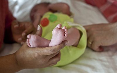 FILE -- In this Nov. 5, 2015 photo, a couple from Britain whose baby was born on Oct. 17 by a surrogate pose their baby for a photo in Anand, India (AP Photo/Allison Joyce)
