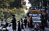 Illustrative: Children and adults cross a street in front of a school bus in Borough Park, a neighborhood in the Brooklyn borough of New York that is home to many ultra-Orthodox Jewish families. (AP/Bebeto Matthews)