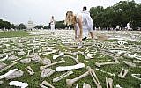 Jess Perkins from Napier, New Zealand, places bones, crafted by students, artists and activists, on the lawn of the National Mall Washington as part of a visible petition for bold action towards an end to genocide and mass atrocities, Saturday, June 8, 2013. (AP/Manuel Balce Ceneta)