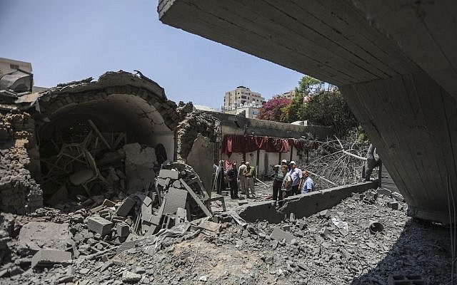 Palestinians walk through the wreckage of a building that was damaged by Israeli air strikes in Gaza City, on July 15, 2018. (Wissam Nassar/ Flash90) Palestinians walk through the wreckage of a building that was damaged by Israeli air strikes in Gaza City, on July 15, 2018. (Wissam Nassar/ Flash90)