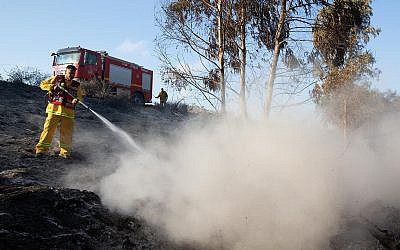 Israeli firefighters extinguish a fire at Shikma Reservoir caused from kites flown by Palestinians, near the border with the Gaza Strip, July 5, 2018. (Edi Israel/Flash90)