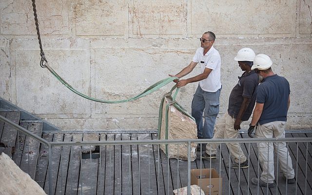 Workers attach a crane to a large chunk of stone dislodged from the Western Wall in Jerusalem Old City, at the mixed-gender prayer section, July 25, 2018. (Hadas Parush/Flash90)