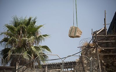 A crane lifts a large chunk of stone dislodged from the Western Wall in Jerusalem Old City, at the mixed-gender prayer section, July 25, 2018. (Hadas Parush/Flash90)