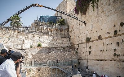 Workers attach a crane to a large chunk of stone dislodged from the Western Wall in Jerusalem Old City, at the mixed-gender prayer section, July 25, 2018. (Hadas Parush/Flash90)