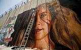 A man paints a mural of Palestinian Ahed Tamimi on a part of Israel's West Bank security barrier in the West Bank city of Bethlehem, July 25, 2018. (Wisam Hashlamoun/Flash90)