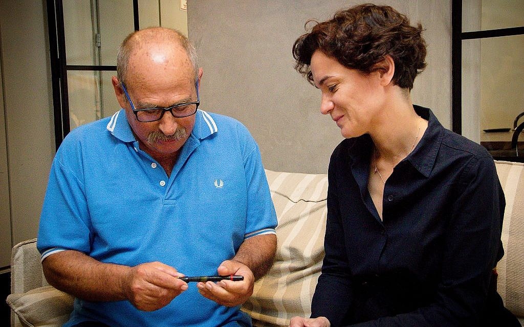Yaron Roksa (left) receives pen that was confiscated from his father by the Nazis from ITS director Floriane Hohenberg, Jaffa, July 3, 2018. (Laura Ben-David/Courtesy of ITS)