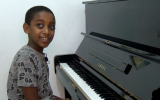 10-year-old Oshri Bitau at his new piano in the family's Nazareth Illit home, July 15, 2018. (Hadashot screen capture)